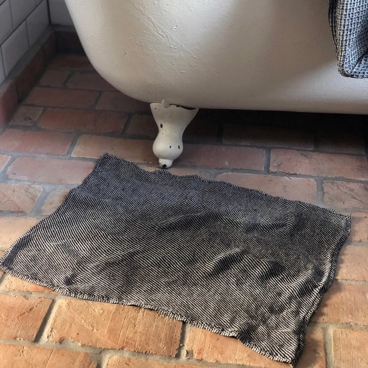En svart torkmatta ligger på ett badrumsgolv