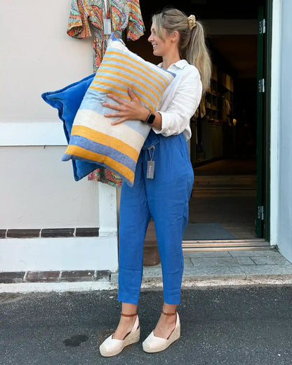 Moellen har på sig blåa linnebyxor och håller i linnekuddar. 