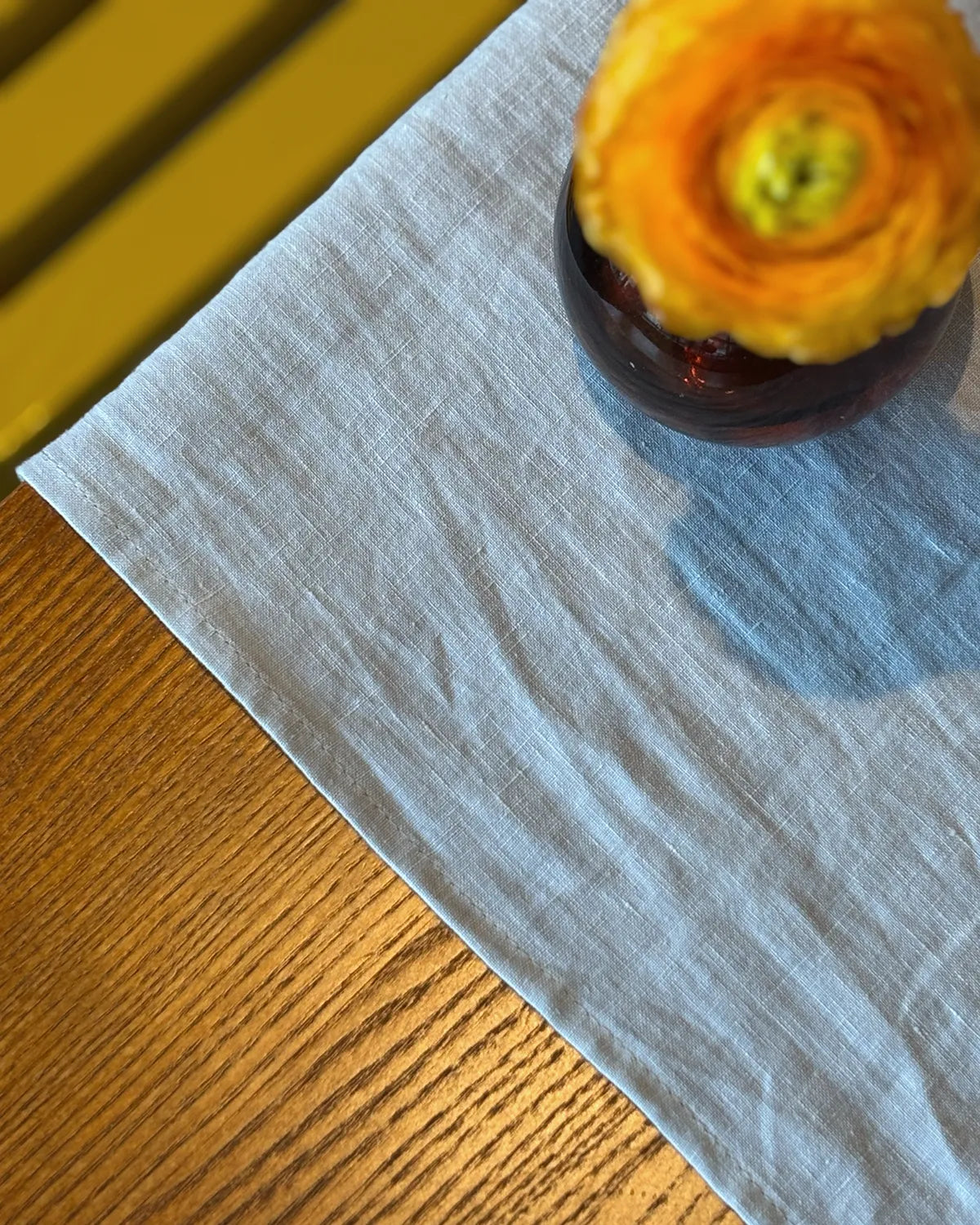 Grått linnetyg och en orange ranukel 