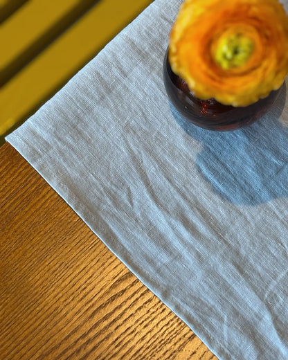 Grått linnetyg och en orange ranukel 