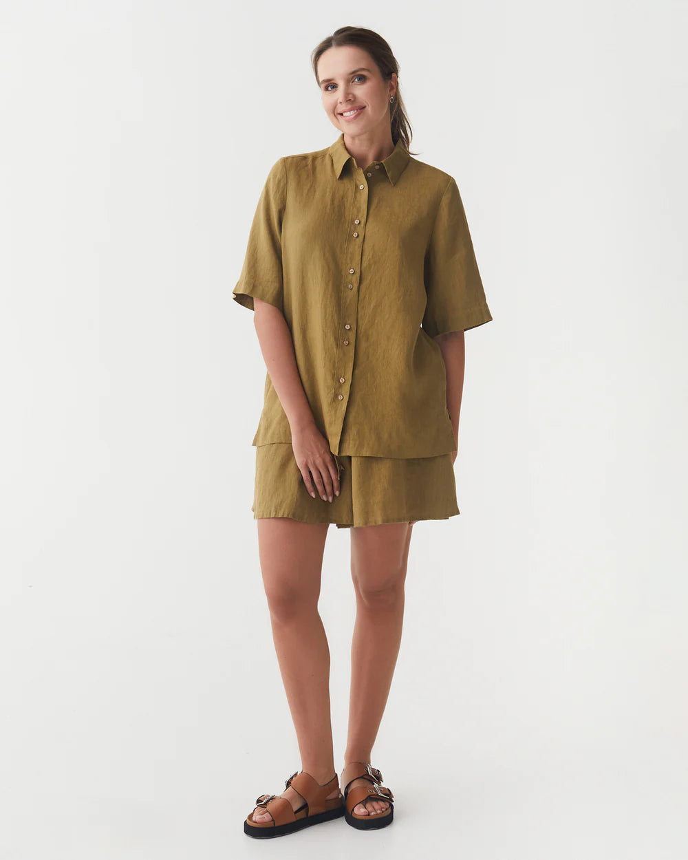 En kvinna har på sig en khakifärgad linneblus och shorts 