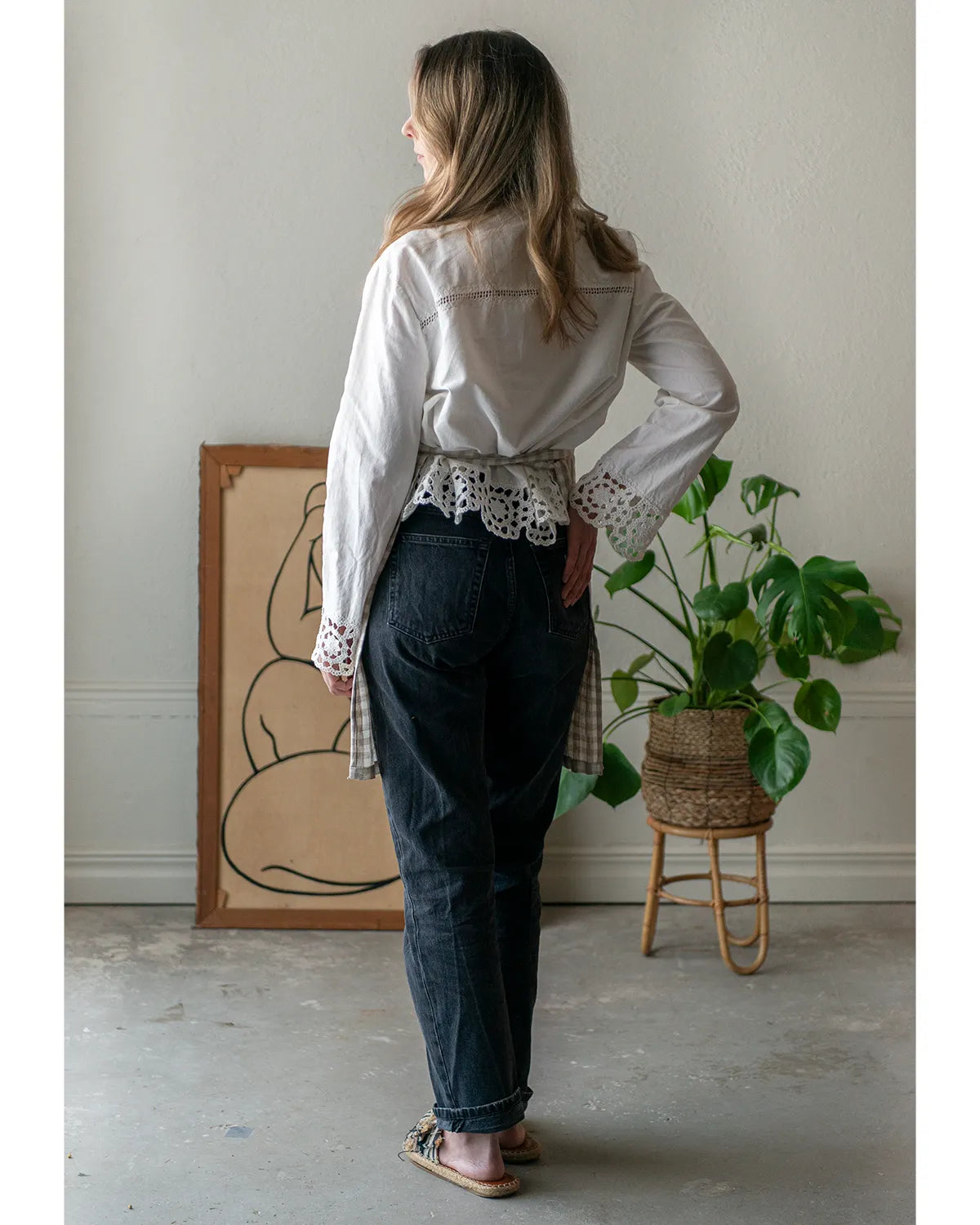 En tjej har på sig en vit blus och mörka jeans 