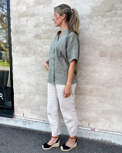 Modell bär kortärmad linneblus med murarkrage och beiga linnebyxor