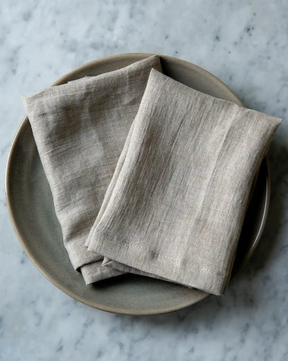 Linnefärgade tygservetter på en beige tallrik