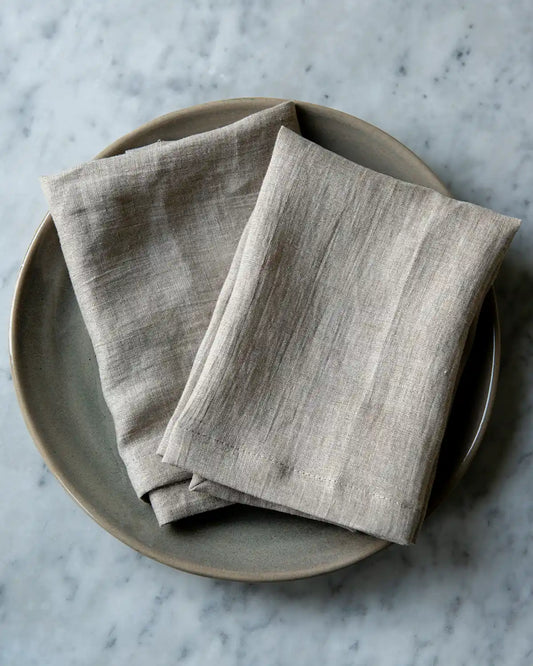 Linnefärgade tygservetter på en beige tallrik