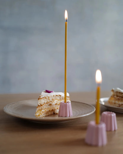 Rosa små porslinsljusstakar med gula bivaxljus