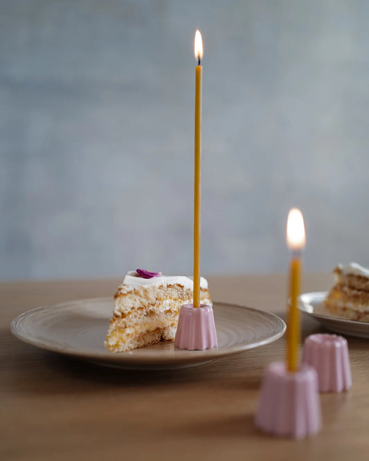 Rosa små porslinsljusstakar med gula bivaxljus