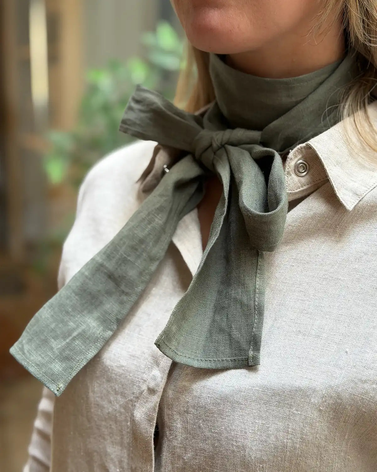En grön scarfs i linne som är knuten som en rosett 