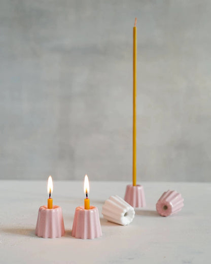 Små keramikljusstakar i rosa och vitt. 