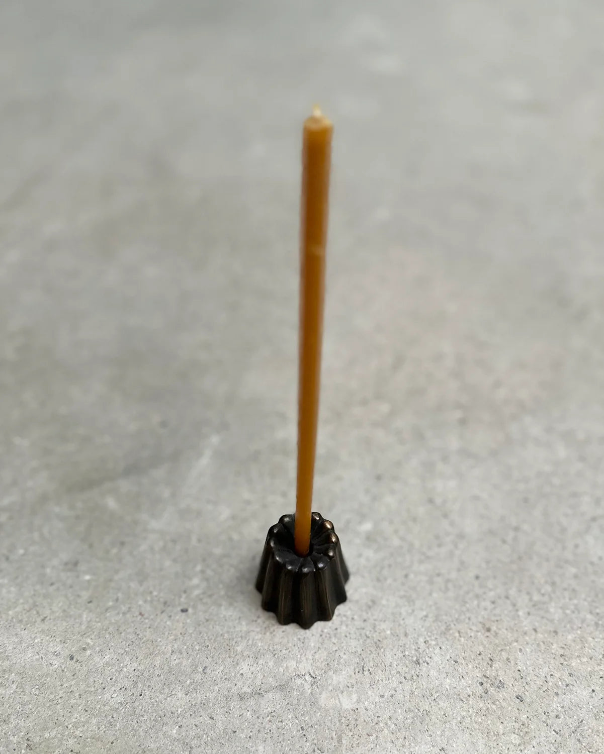 Ett smalt bivaxljus i en liten svart ljusstake 