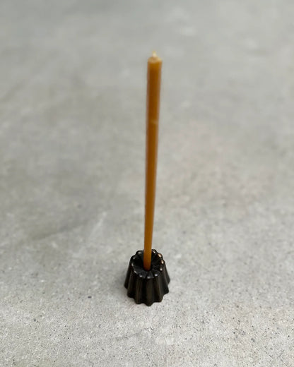 Ett smalt bivaxljus i en liten svart ljusstake 
