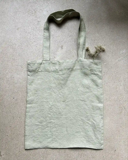 En tygpåse i grönt med långa handtag 