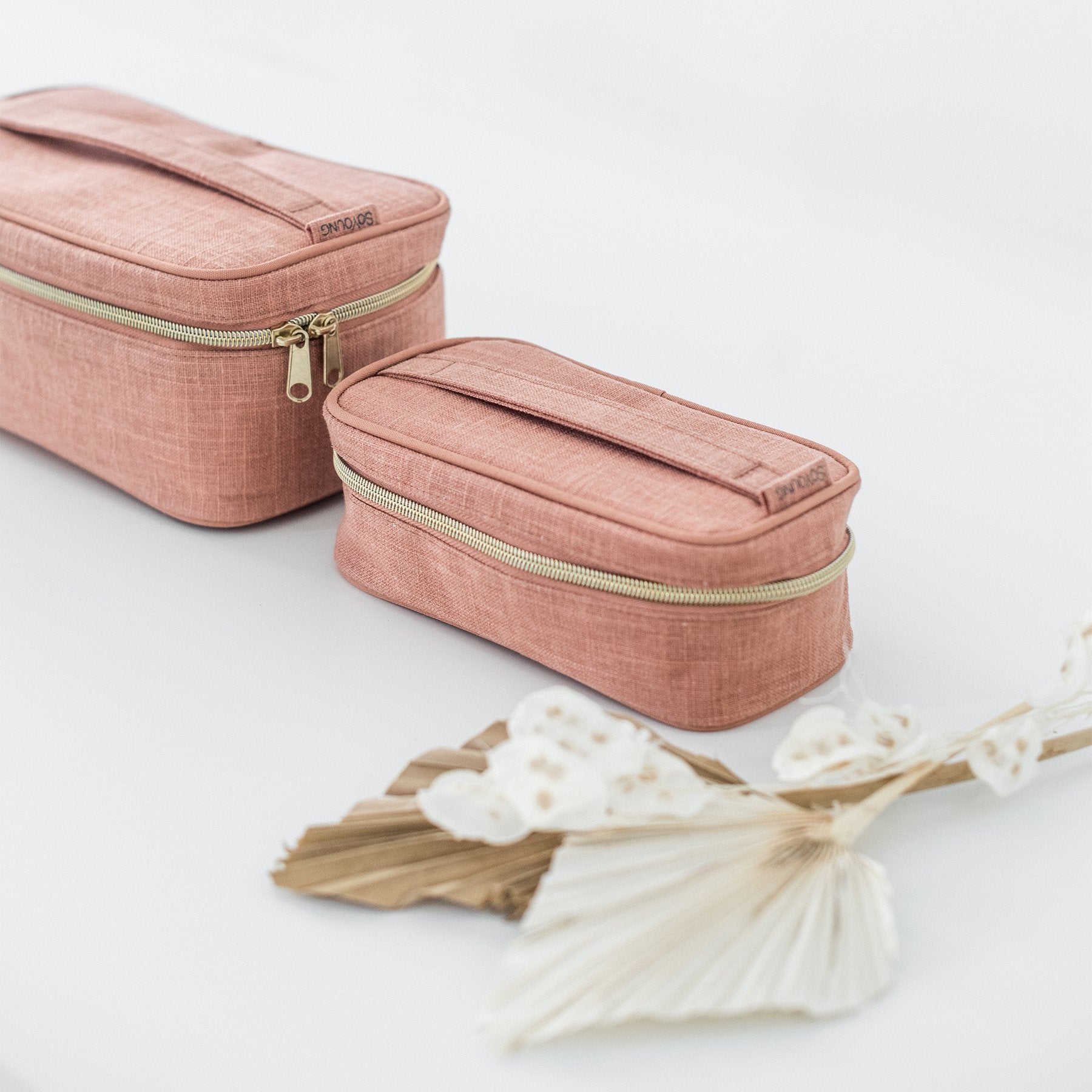 Två handsydda necessär i rosa linne med dragkedja.