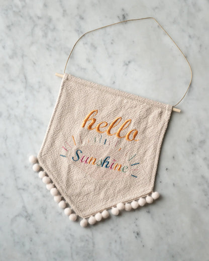 En handsydd vimpel i linne med ett broderat budskap.