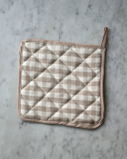 En handsydd rutig grytlapp i linne med beige och vita rutor. 